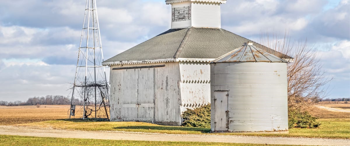 A windmill and a barn in a rural setting.
