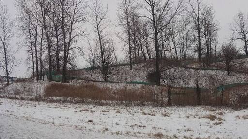 A snow covered abandoned water slide just seemingly plopped in the middle of a farm field along interstate 71. Maybe a one time campground or RV park?