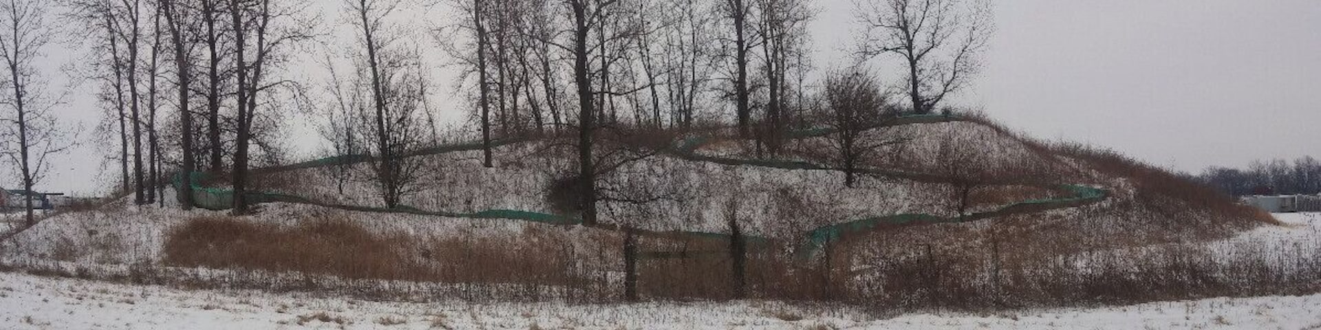 A snow covered abandoned water slide just seemingly plopped in the middle of a farm field along interstate 71. Maybe a one time campground or RV park?