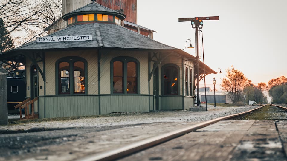 A historic train station named Canal Winchester with a distinctive green roof and arched windows.
