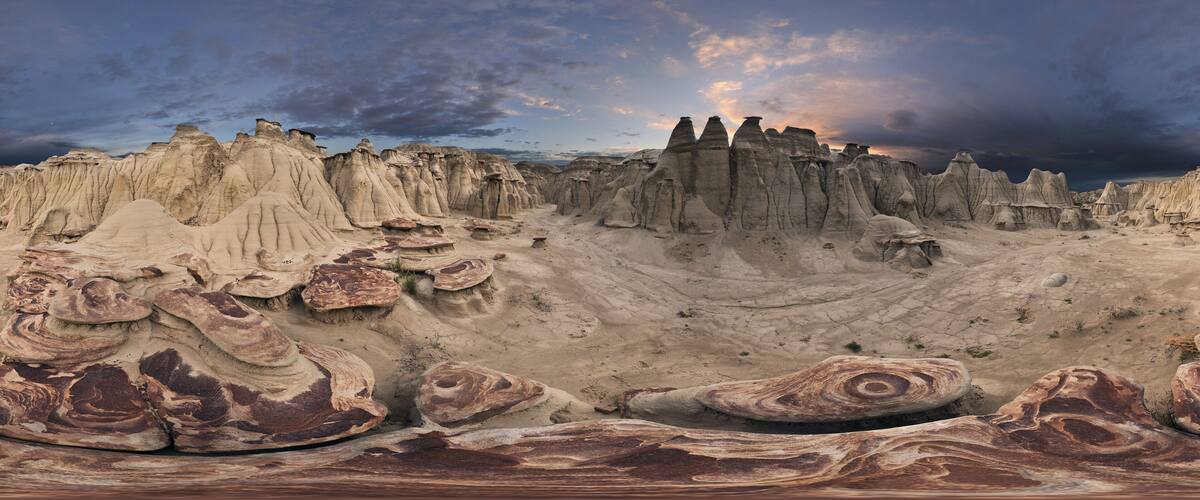 A vast landscape of eroded rock formations with a dramatic sky.
