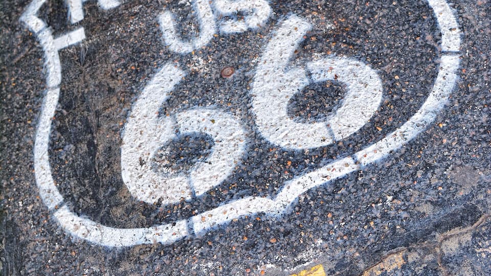 A road sign with the text "ROUTE US 66" painted on the asphalt.
