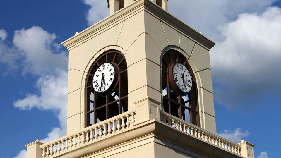 A clock tower with two large clocks and an arched entrance.