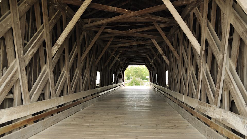 A covered wooden bridge with a wooden floor and metal railings.