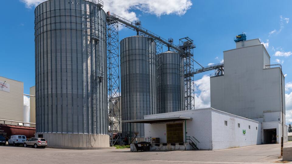 Industrial silos, a white building, and a clear blue sky.