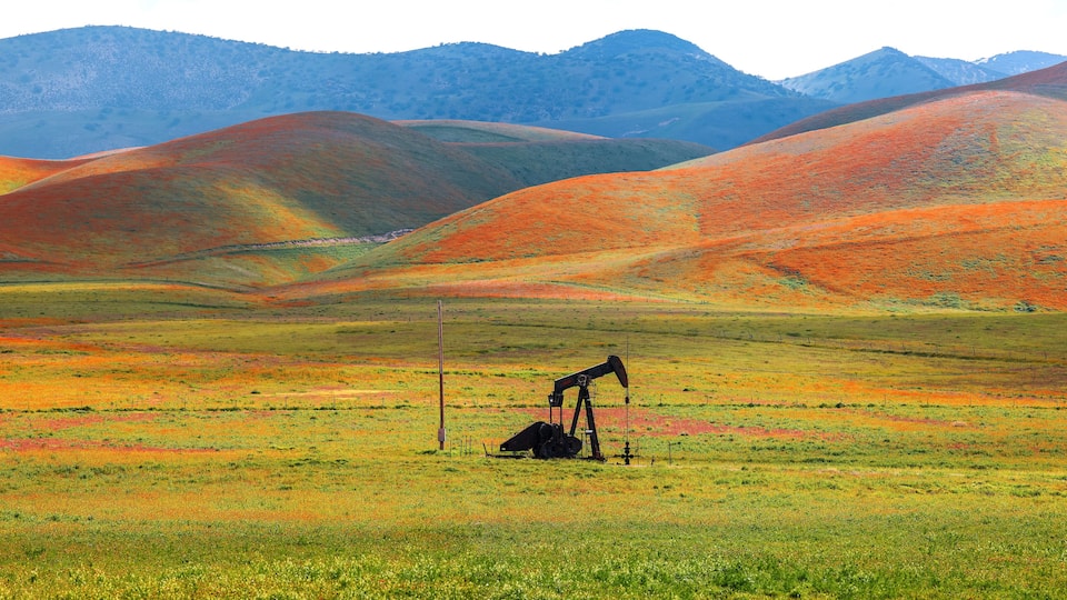 A colorful landscape with rolling hills and an oil pumpjack in the foreground.