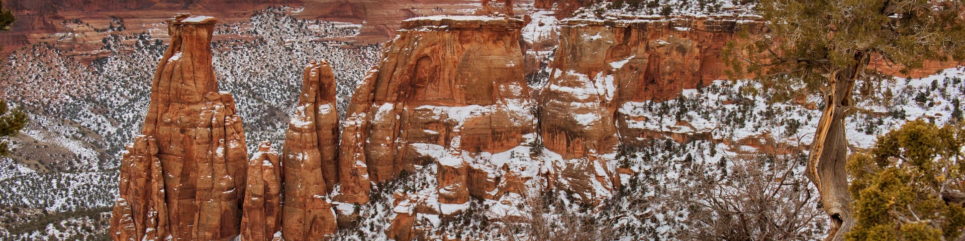 A snow-covered landscape with red rock formations and a sunset.
