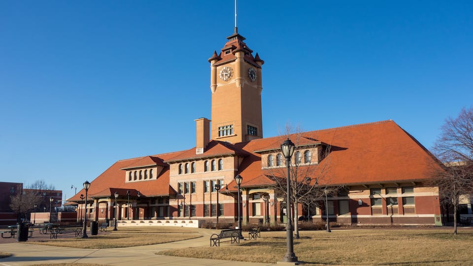 A large brick building with a clock tower and a flag on top.