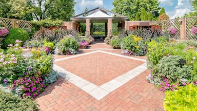 Um jardim com um caminho de tijolos que leva a um gazebo.