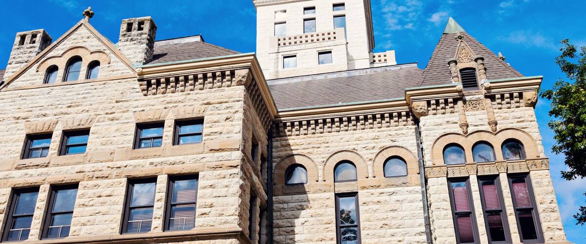 A historic stone building with a prominent tower and multiple windows.