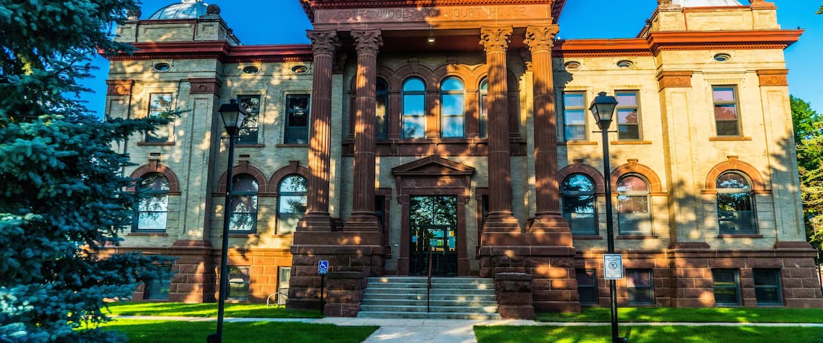A large, historic building with a prominent dome and columns, surrounded by well-maintained lawns and trees.
