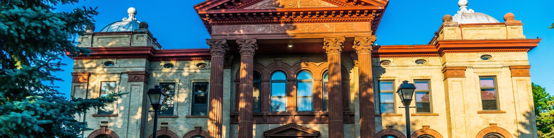 A large, historic building with a prominent dome and columns, surrounded by well-maintained lawns and trees.