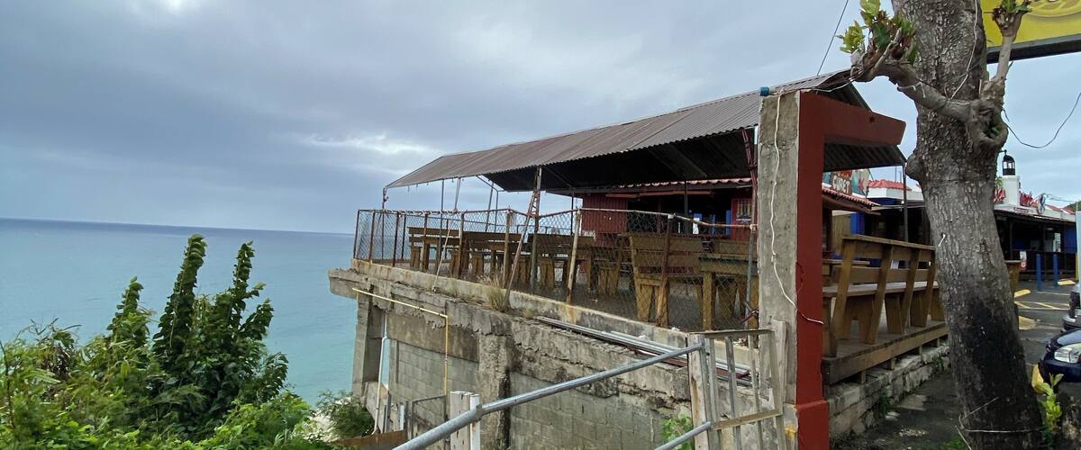 A coastal restaurant with a view of the ocean, a tree, and a sign for 'Meda Light'.