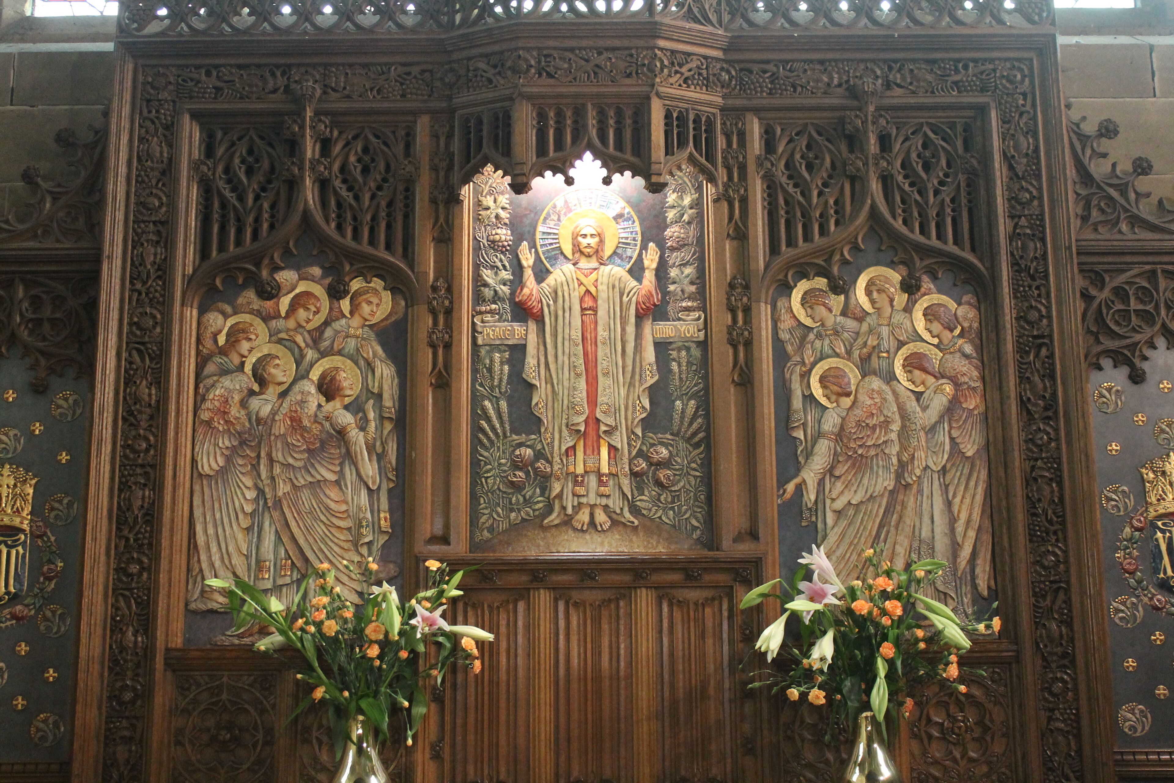 A religious iconostasis with intricate carvings and floral arrangements.