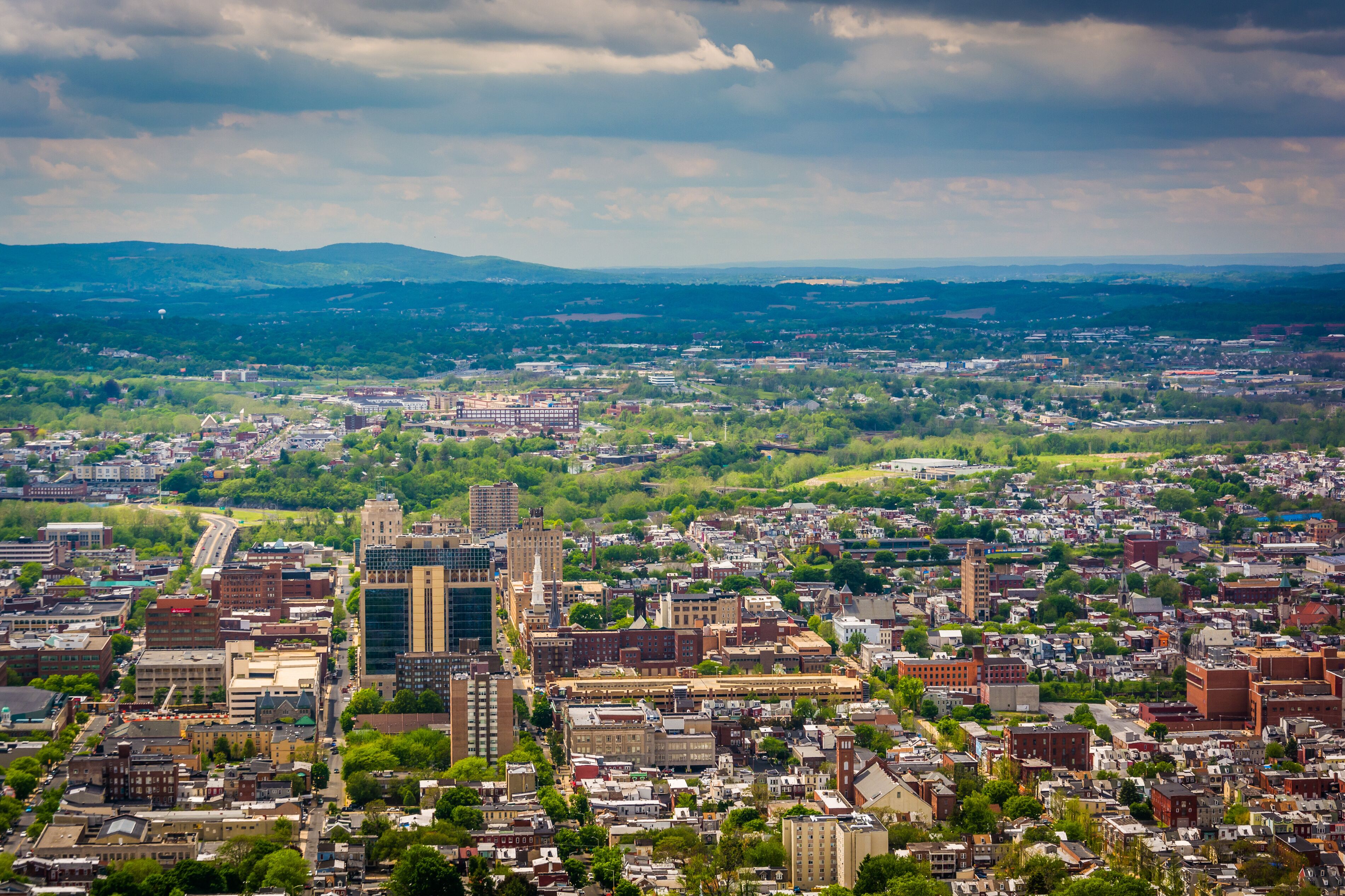A cityscape with a mix of modern and historic buildings, a river, and rolling hills in the distance.