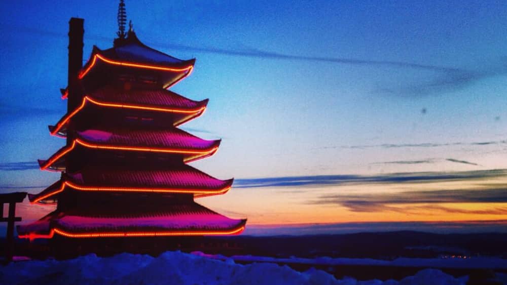 A pagoda with illuminated red lights against a twilight sky.
