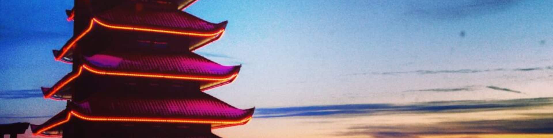 Um pagode com luzes vermelhas iluminadas contra o céu crepuscular.