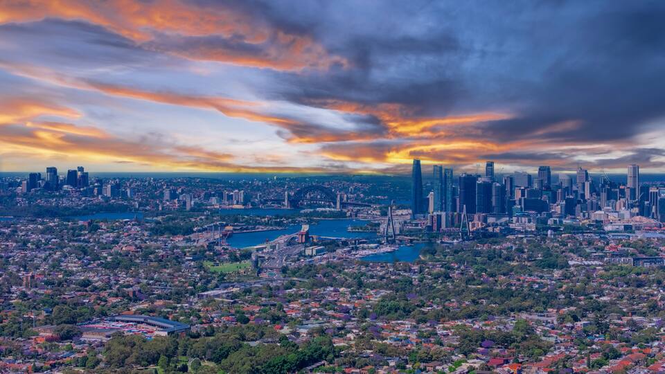 A cityscape with a prominent skyline, a large body of water, and surrounding greenery.