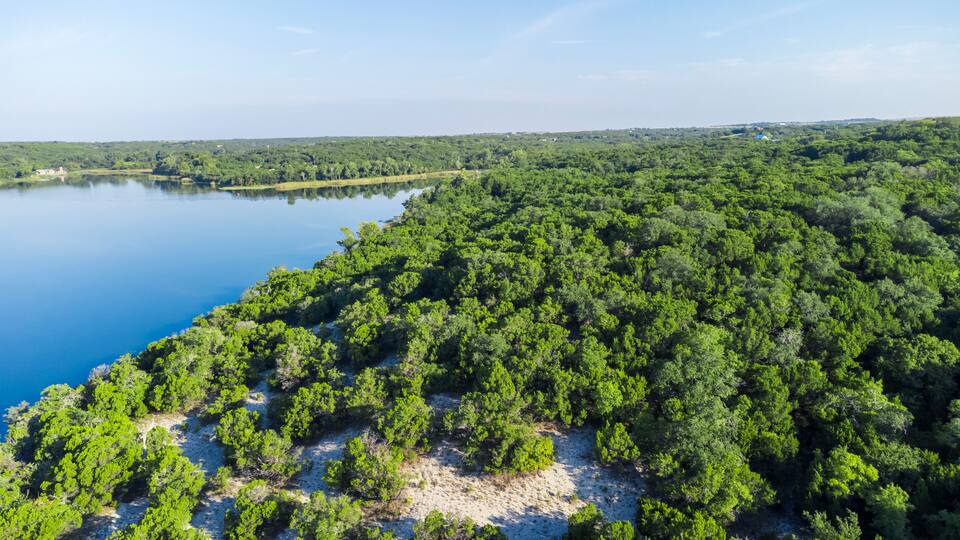 A lake surrounded by dense forest and a sandy beach area.