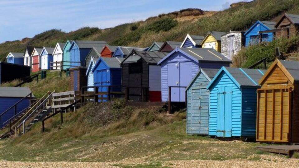 A row of colorful beach huts on a hillside.