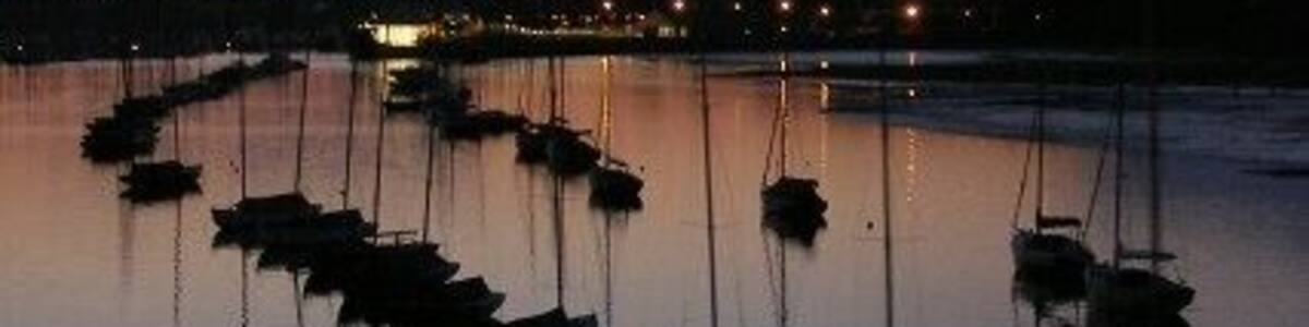 Ein ruhiger Hafen im Abendlicht, mit mehreren Booten vor Anker.