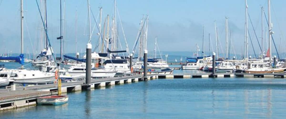 Un port de plaisance où de nombreux voiliers sont amarrés le long d’une jetée.