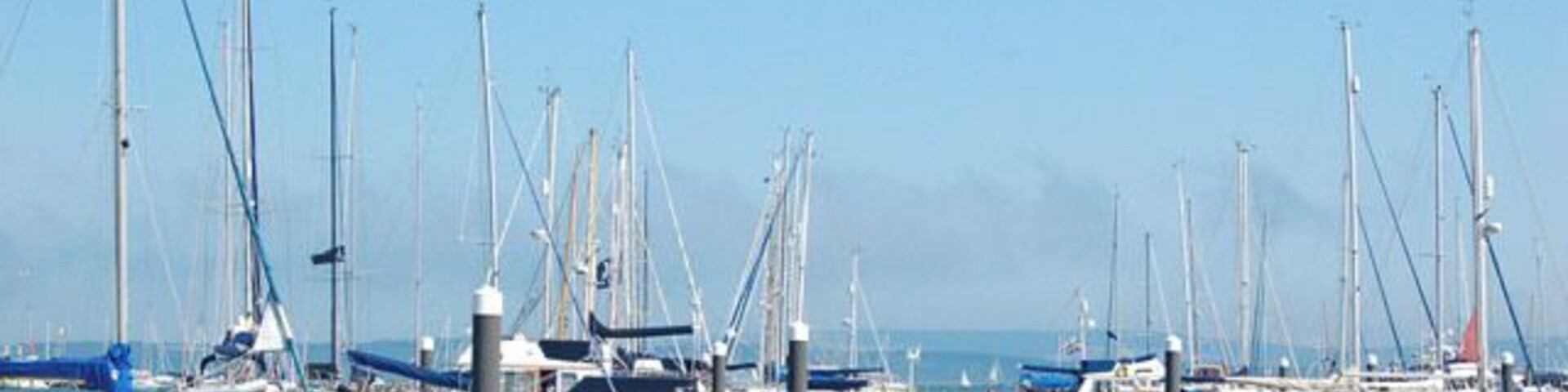 A marina with numerous sailboats docked along a pier.