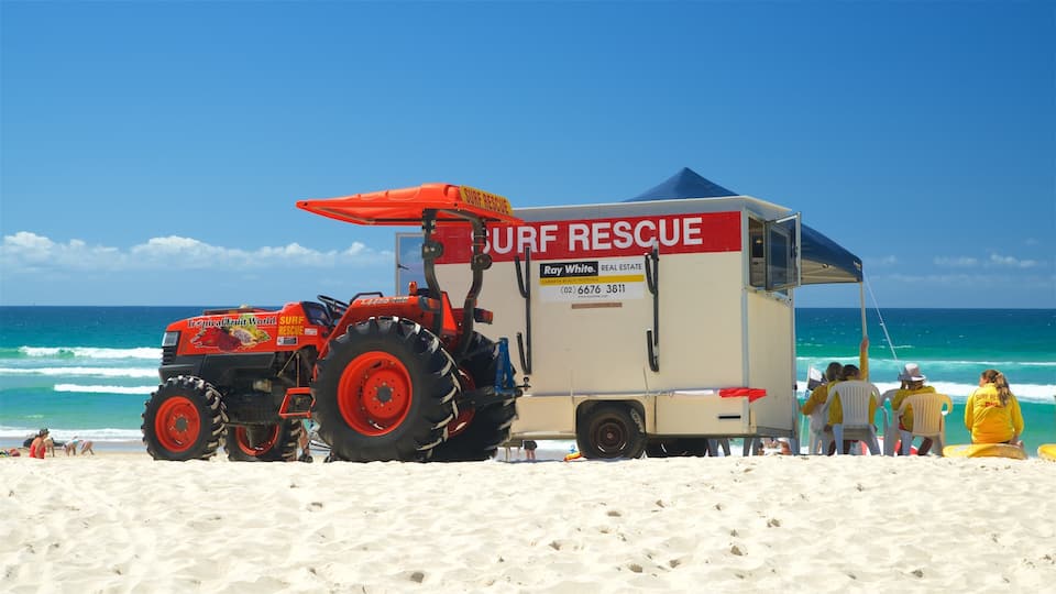 Ein Strand mit einem Rettungswagen für Surfende und Personen in gelben Jacken.