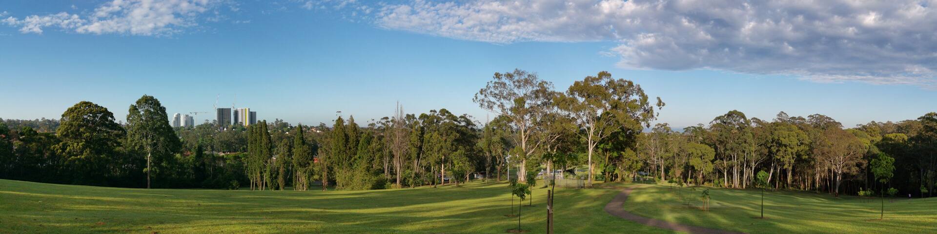 Beautiful panoramic view of a park with green grass and tall trees and deep blue sky with light clouds in the background, Heritage park, Castle Hill, Sydney, New South Wales, Australia
