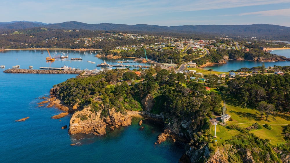 Une ville côtière dotée d’un port de plaisance, d’une côte rocheuse et entourée de collines.