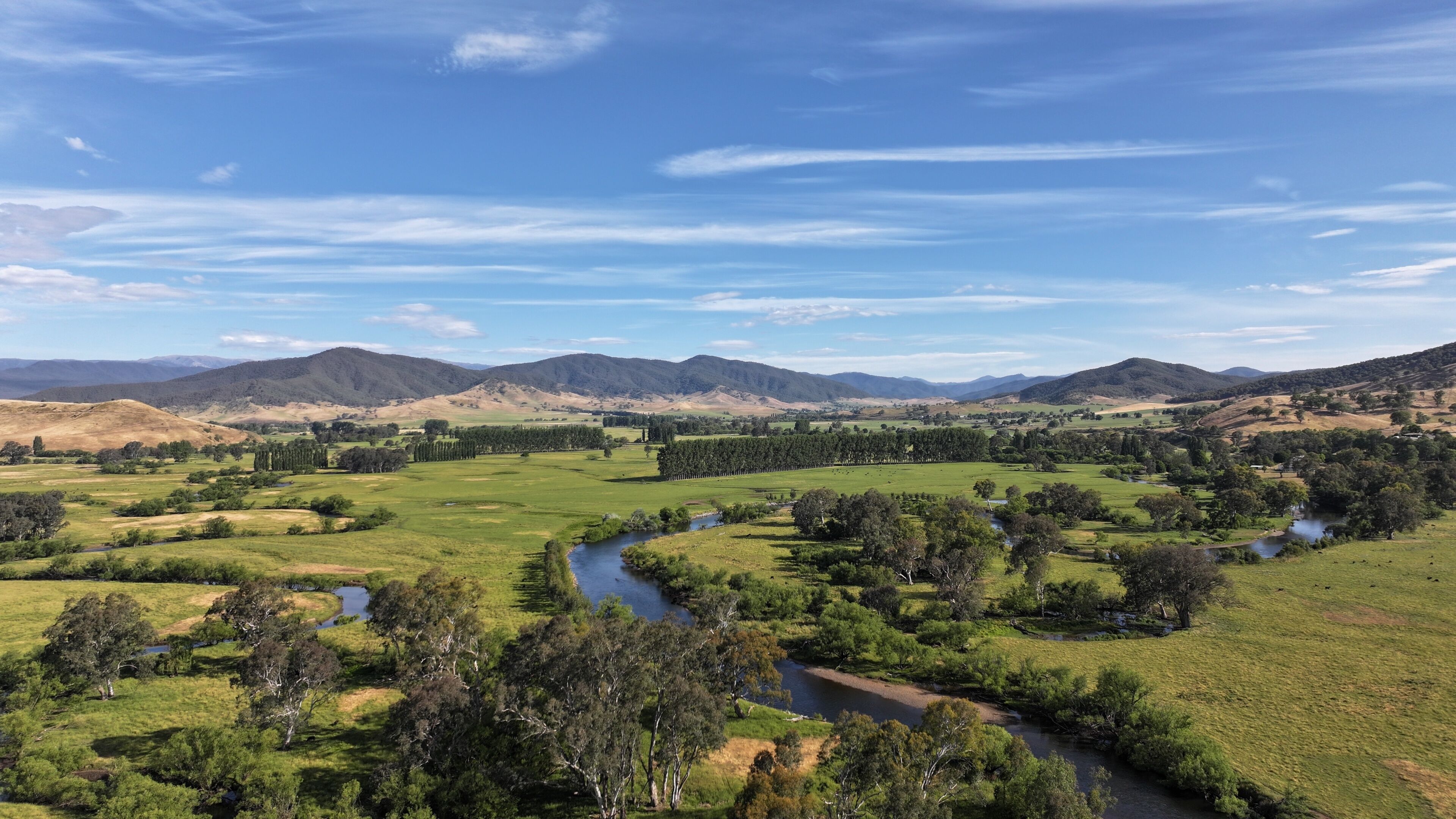 A river winding through a green valley with hills in the background.