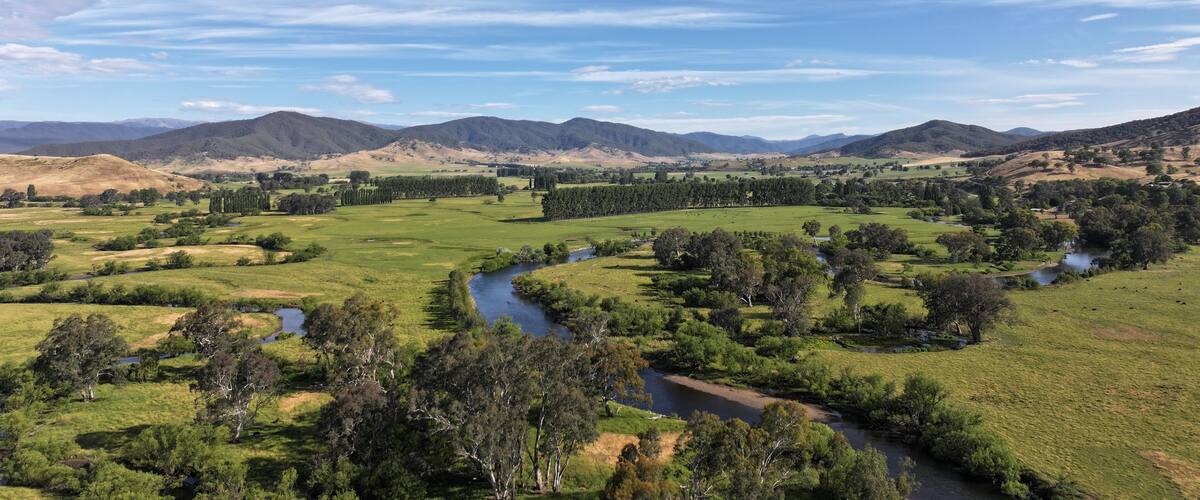 A river winding through a green valley with hills in the background.