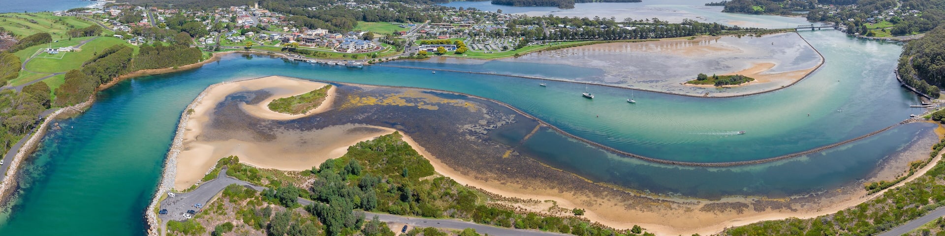 Aerial panorama of a winding river system flowing past a coastal township