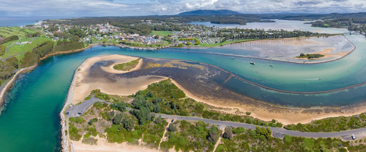 A coastal town with a river, sandy beaches, and a bridge connecting two areas.
