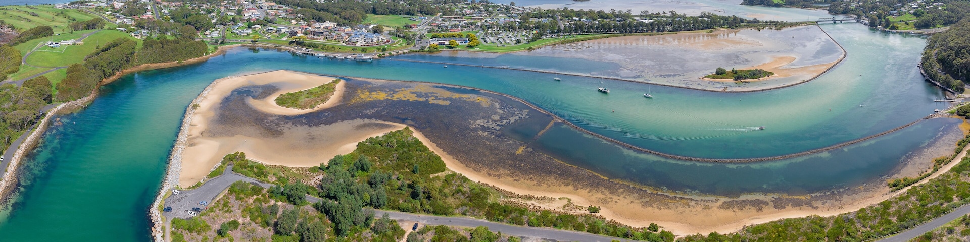 A coastal town with a river, sandy beaches, and a bridge connecting two areas.