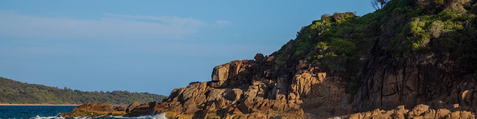 Nelson Bay which includes general coastal views, a sandy beach and rocky coastline