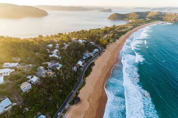 A coastal landscape with a winding road, beachfront, and dense greenery.