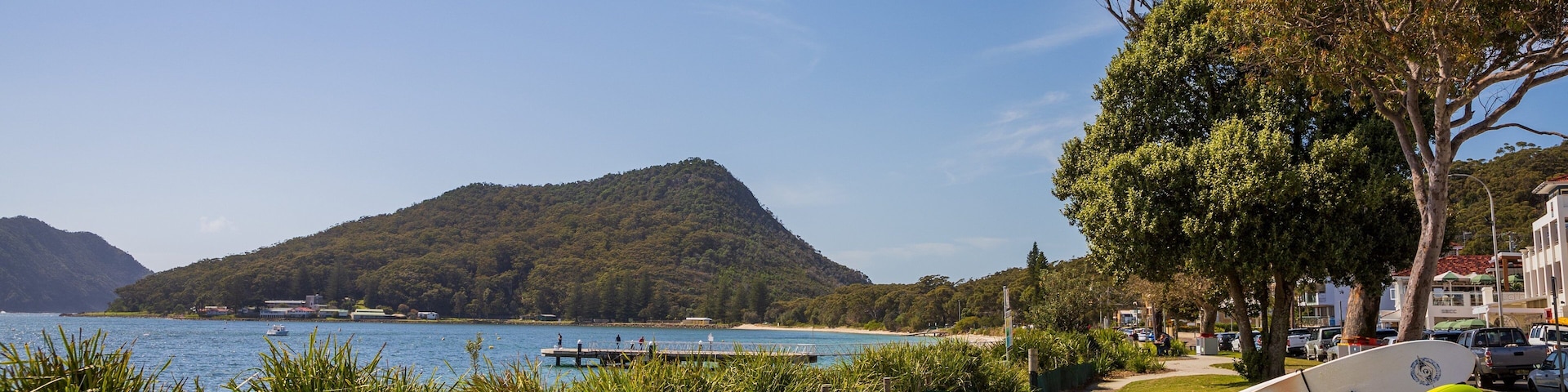 A lakeside view with a bench, paddleboards, and kayaks.