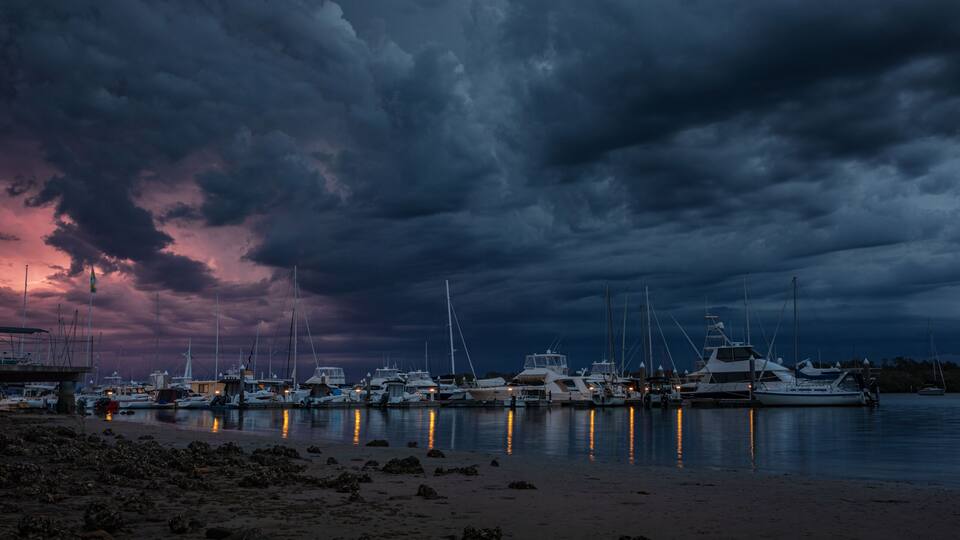 A marina with boats docked under a dramatic sky.