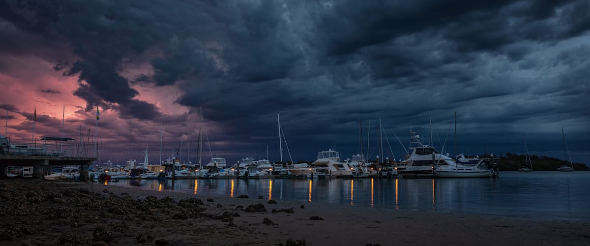 A marina with boats docked under a dramatic sky.