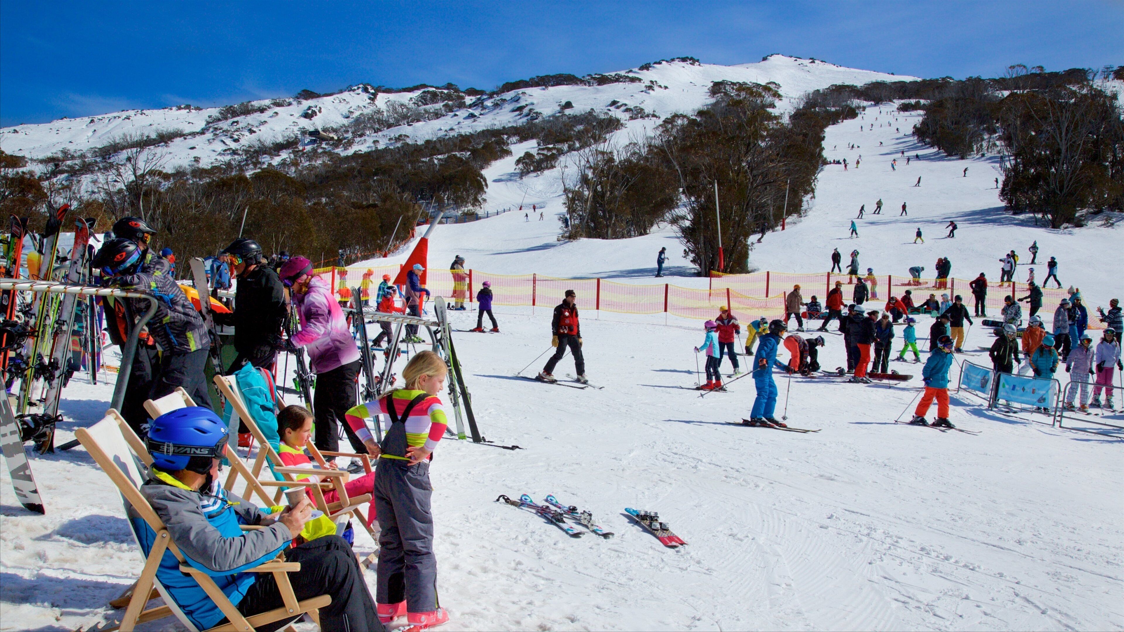 A snowy ski slope with people skiing and standing around.