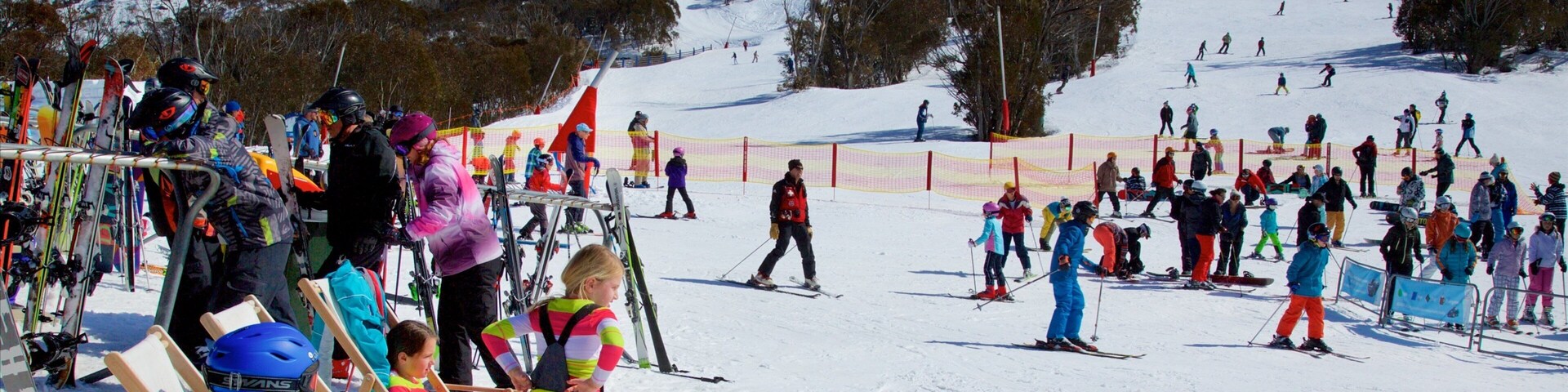 Pista de esquí nevada con gente esquiando y conversando.