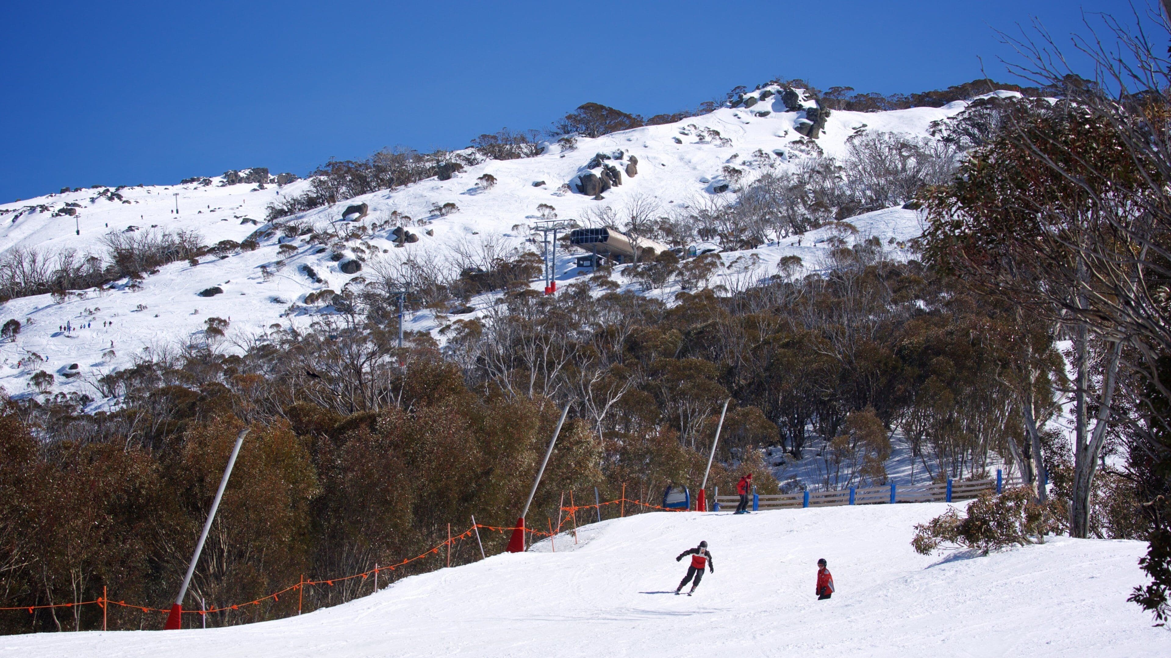 A snowy mountain slope with skiers and a ski lift.