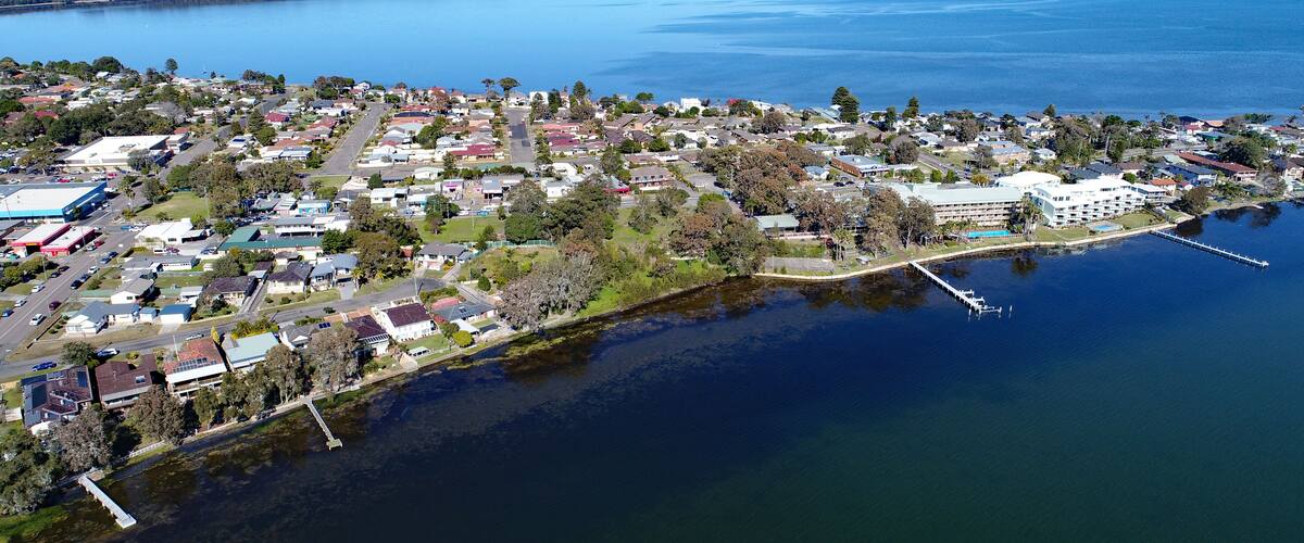 An aerial view of a coastal town with a marina, residential areas, and a large body of water.