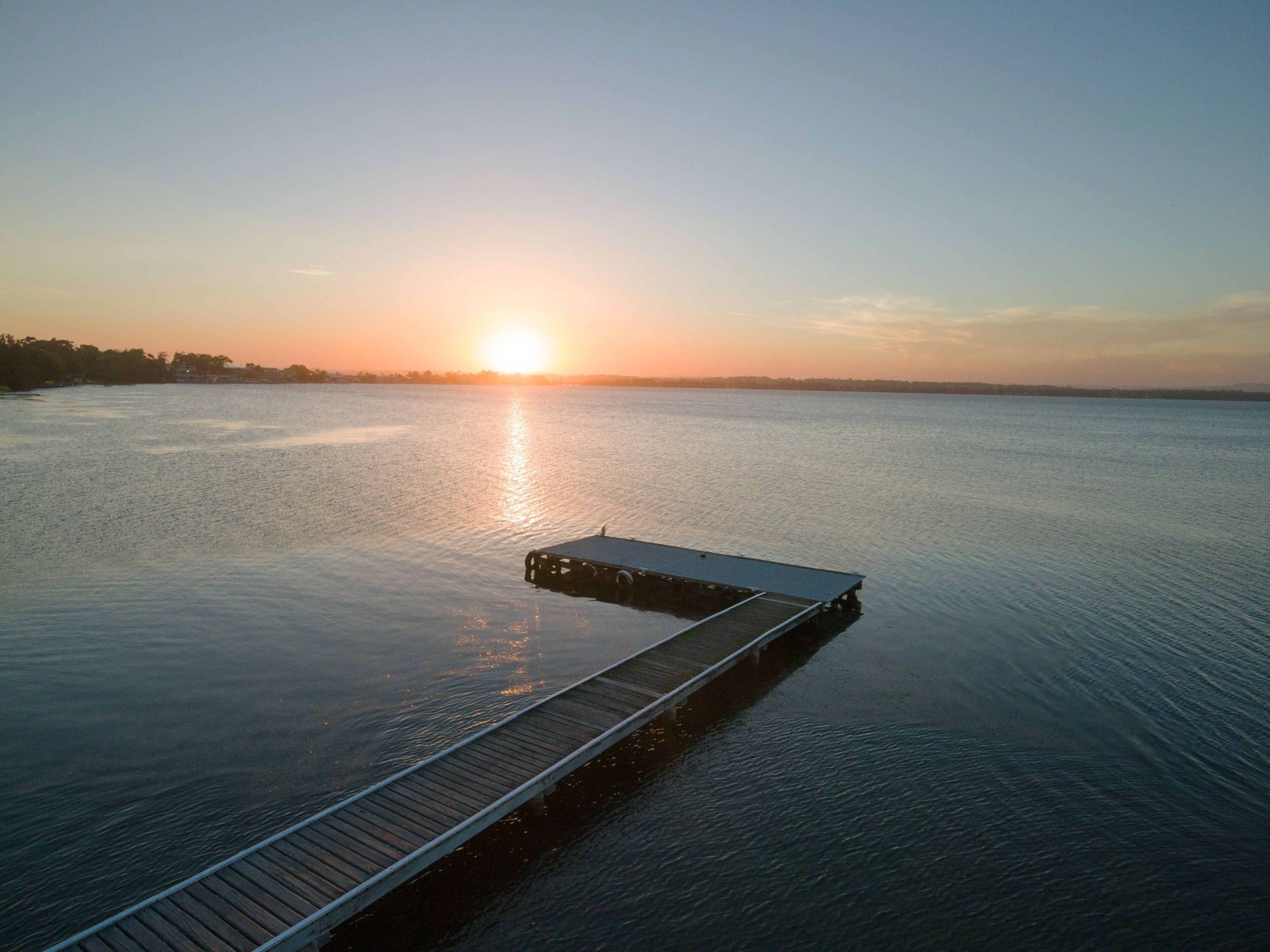 Aerial view of a wooden dock on Toukley lake at sunset in Australia
