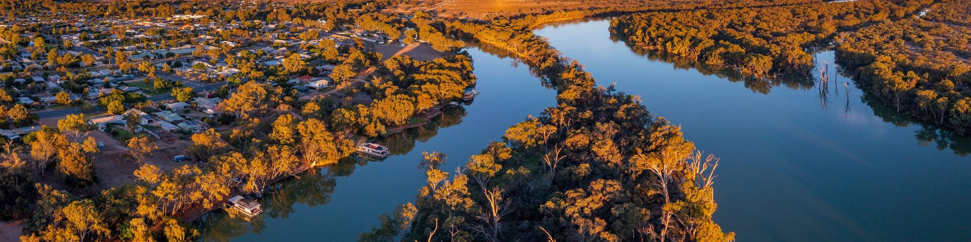 A river winding through a densely wooded area with a small town on one side.