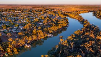 A river winding through a densely wooded area with a small town on one side.