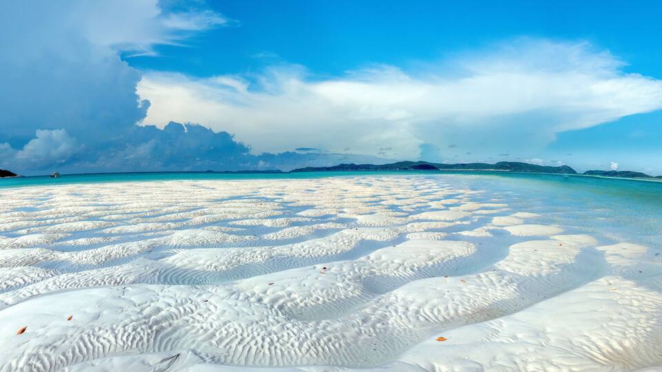 A beach with white sand and clear turquoise water.