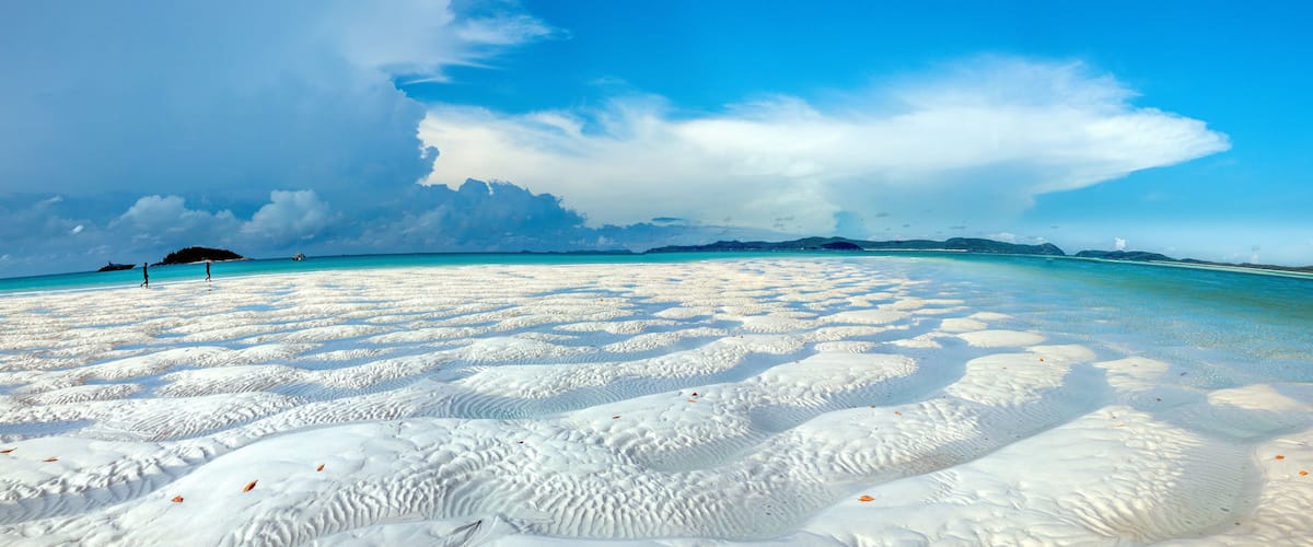 A beach with white sand and clear turquoise water.