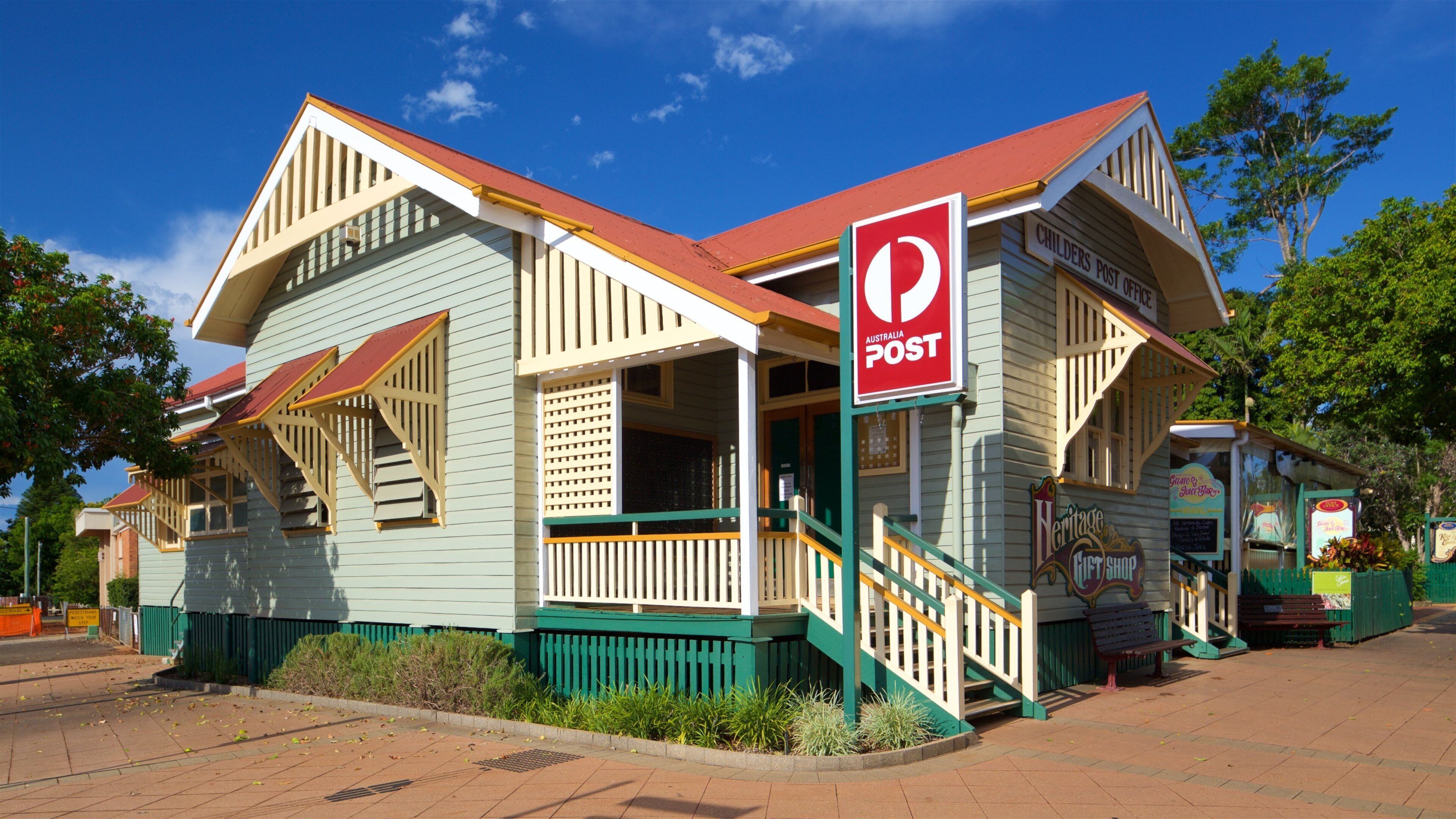 A heritage post office building with a red roof and green trim.